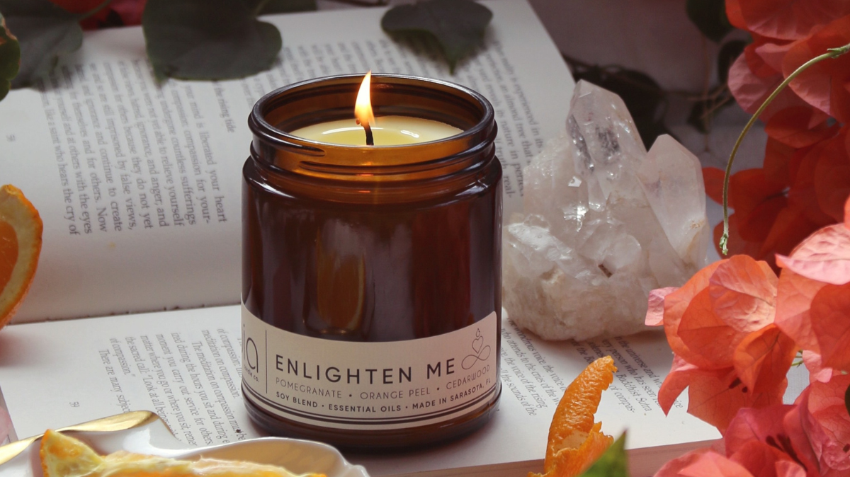 scent candle is burning and there surronding is flowers and its on the book showing the Bia candle co magnificent product