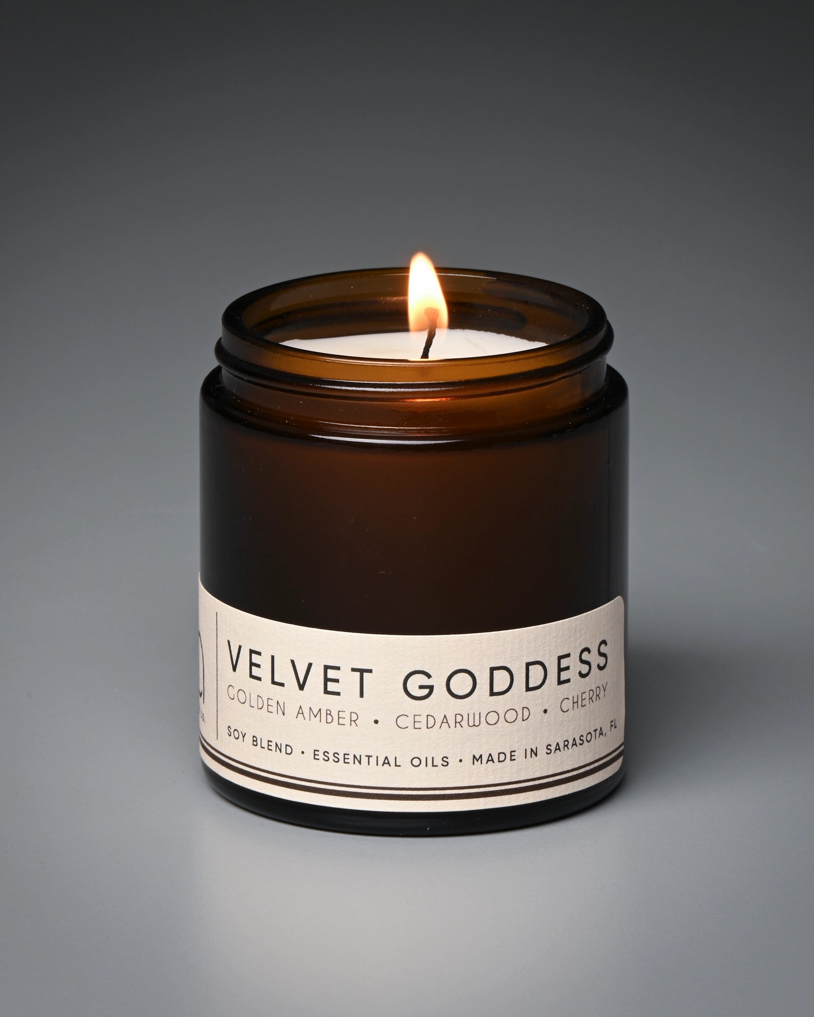 Candle in a brown jar labeled 'Velvet Goddess' on a gray background