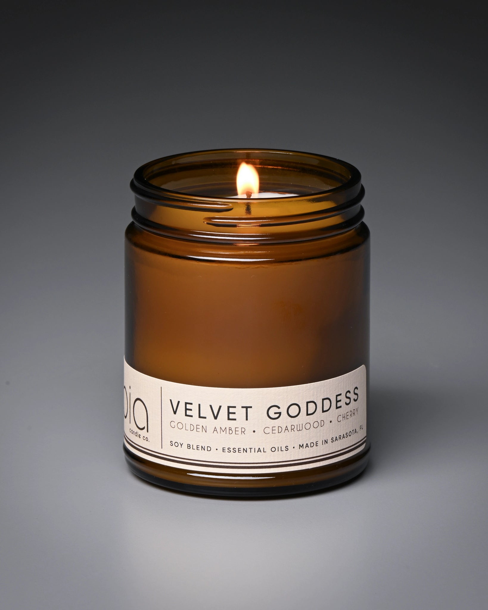 Candle in an amber jar labeled 'Velvet Goddess' on a gray background