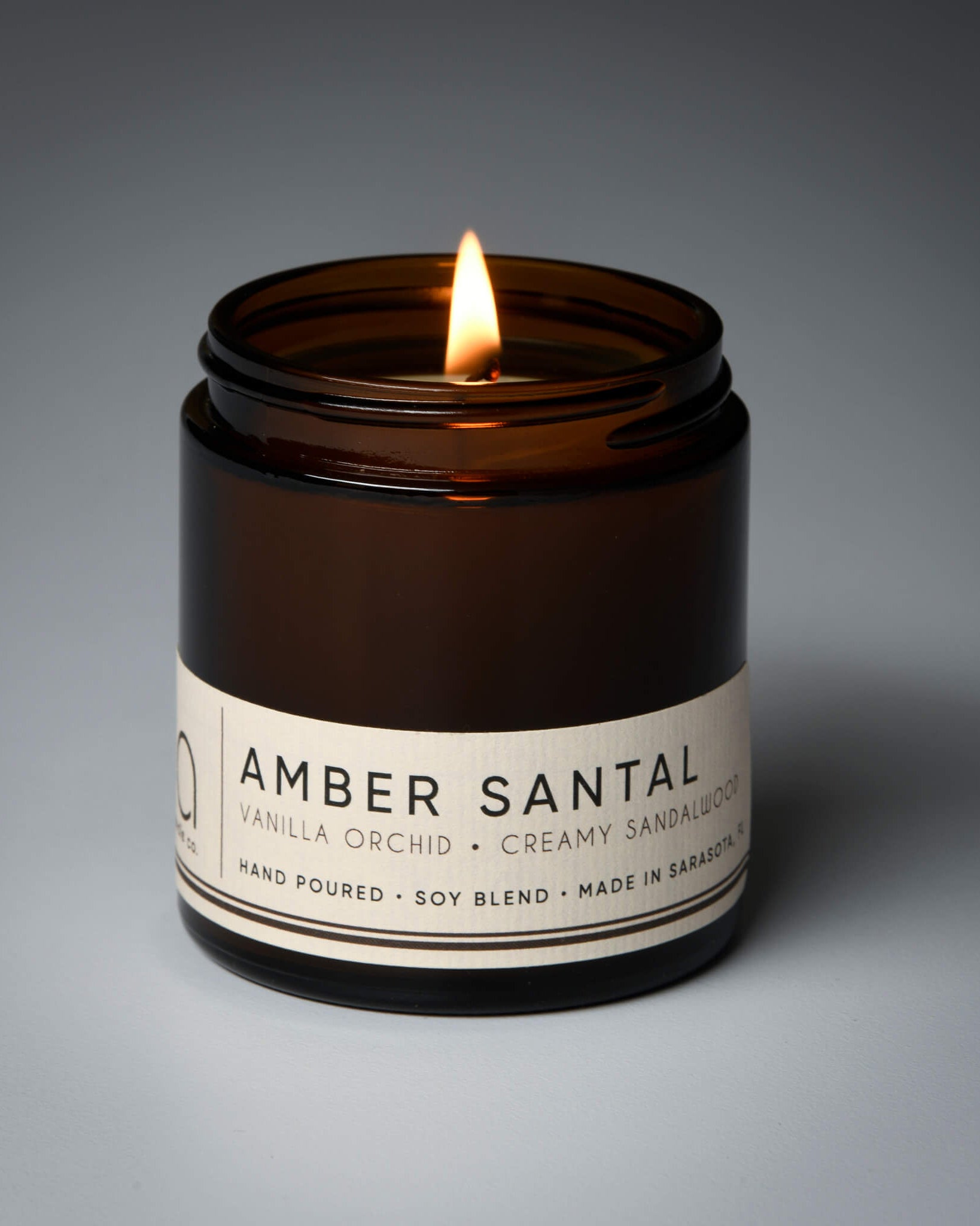 lit petite single wick amber santal soy candle on grey background
