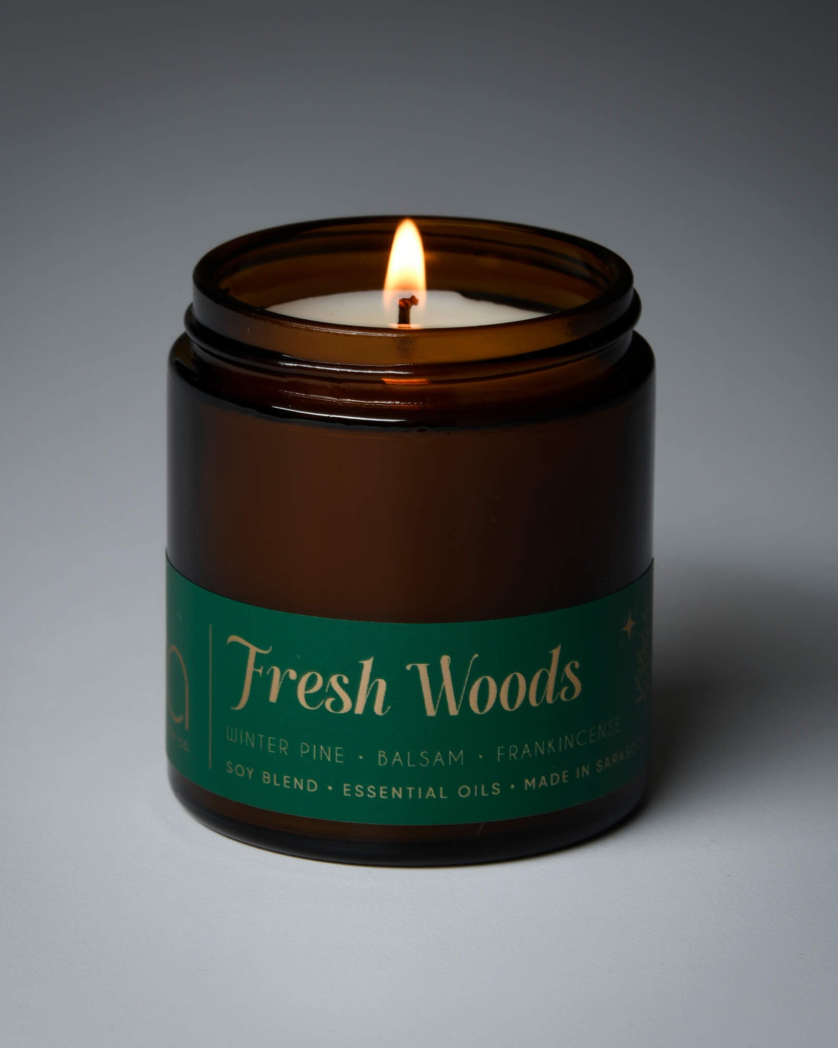 lit petite single wick holiday fresh woods soy candle on grey background