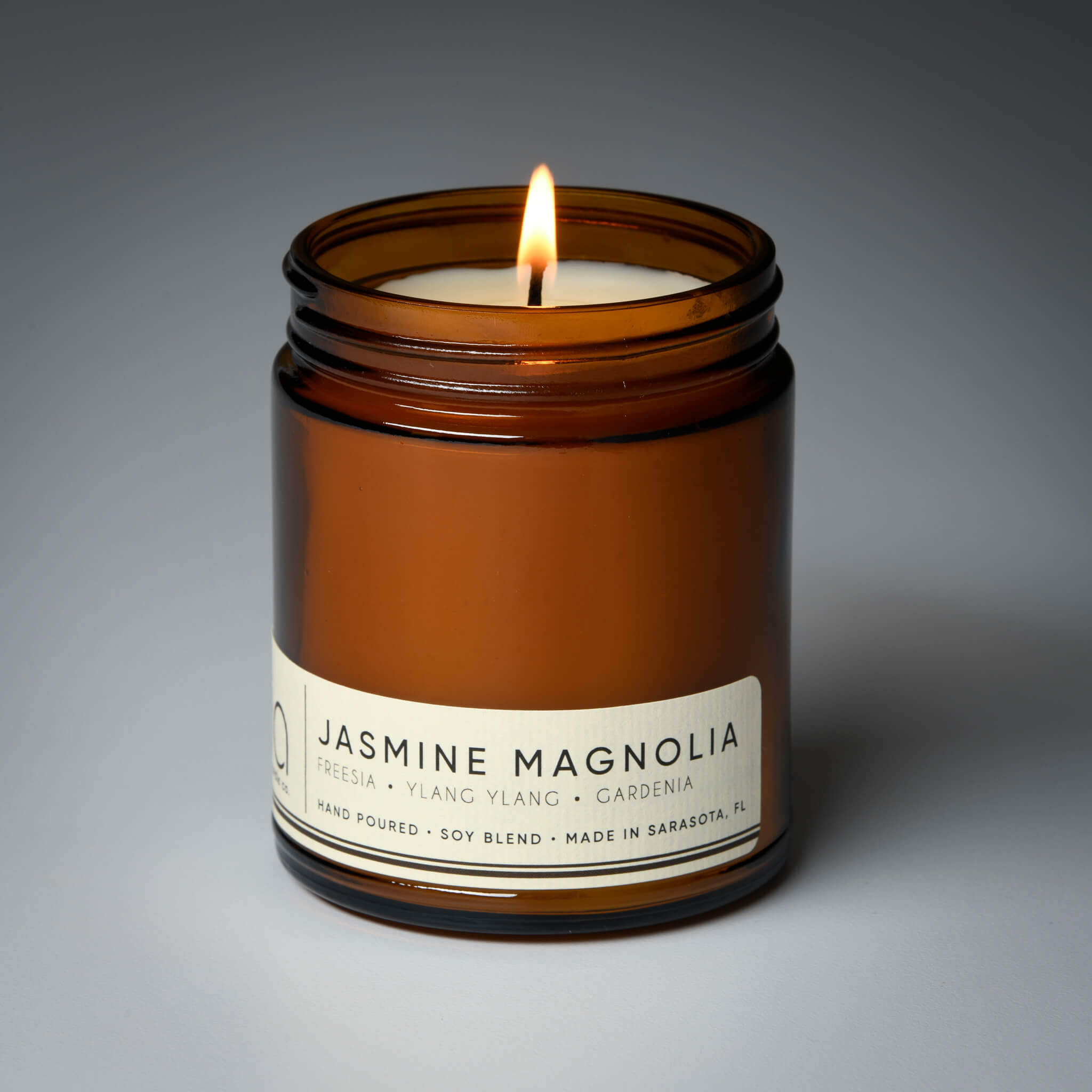 lit single wick jasmine magnolia soy candle on grey background