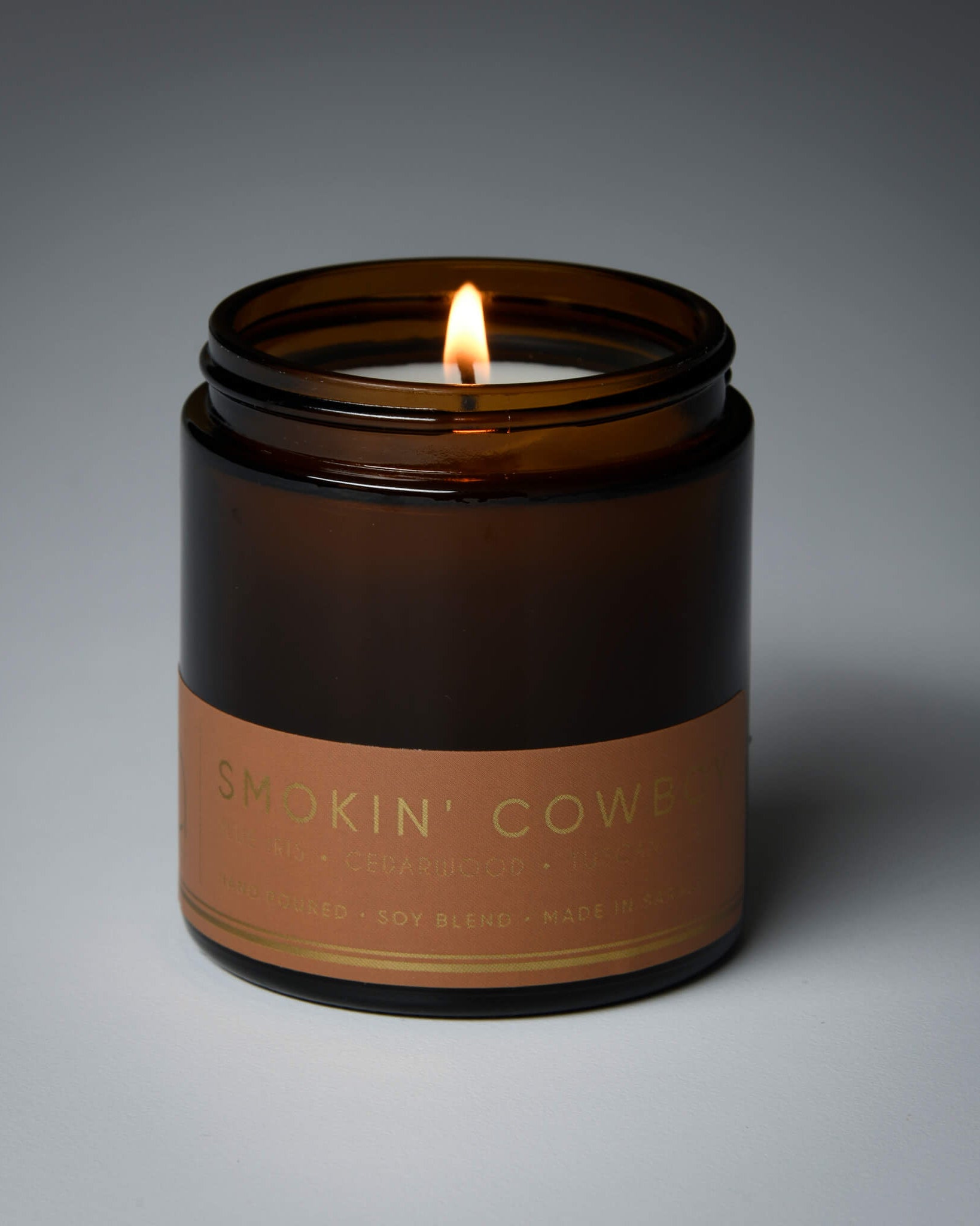 lit petite single wick smokin cowboy soy candle on grey background