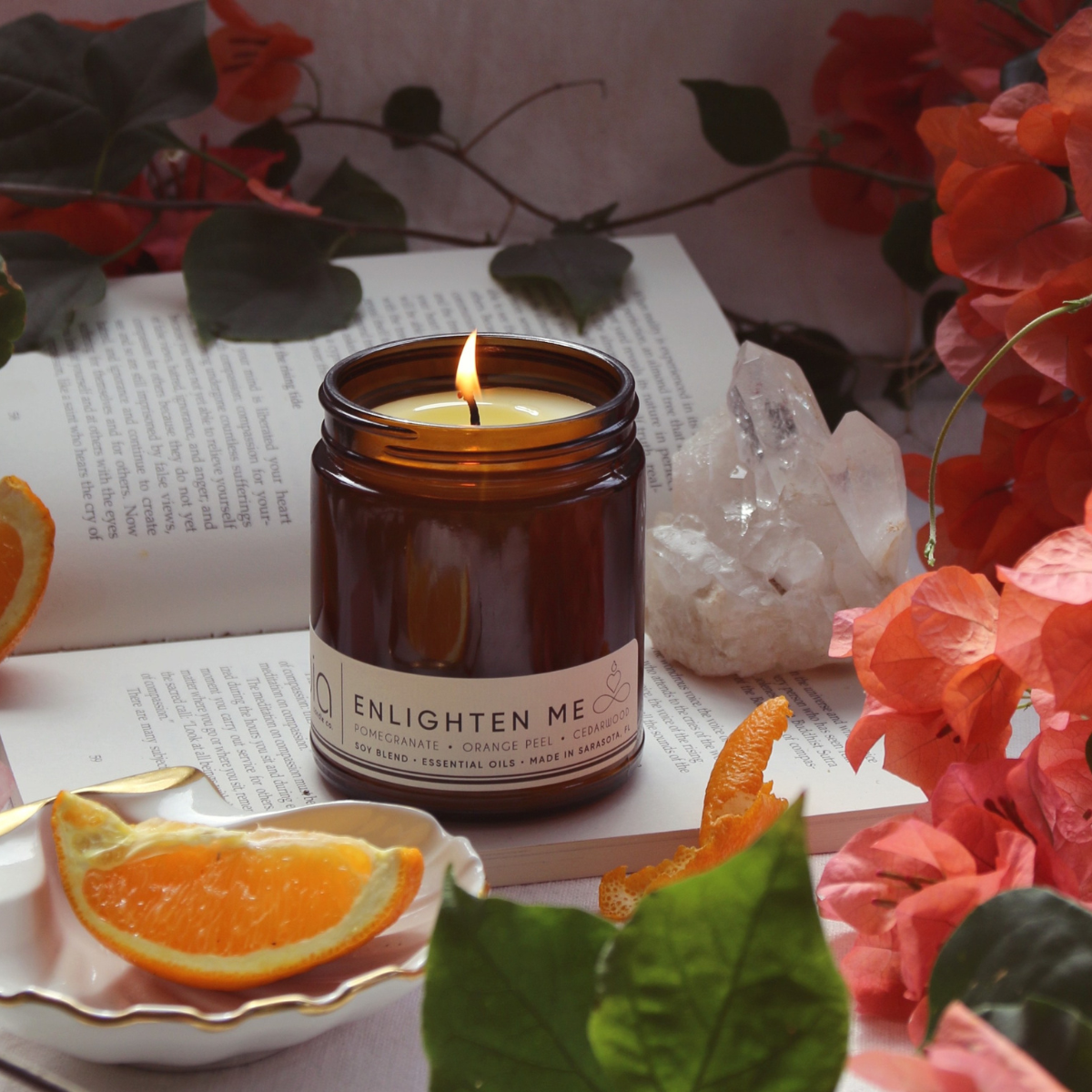 scent candle is burning and there surronding is flowers and its on the book showing the Bia candle co magnificent product