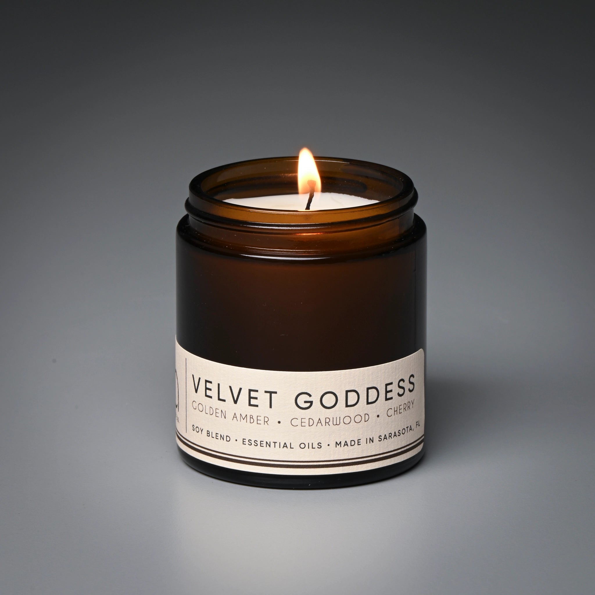 Candle in a brown jar labeled 'Velvet Goddess' on a gray background