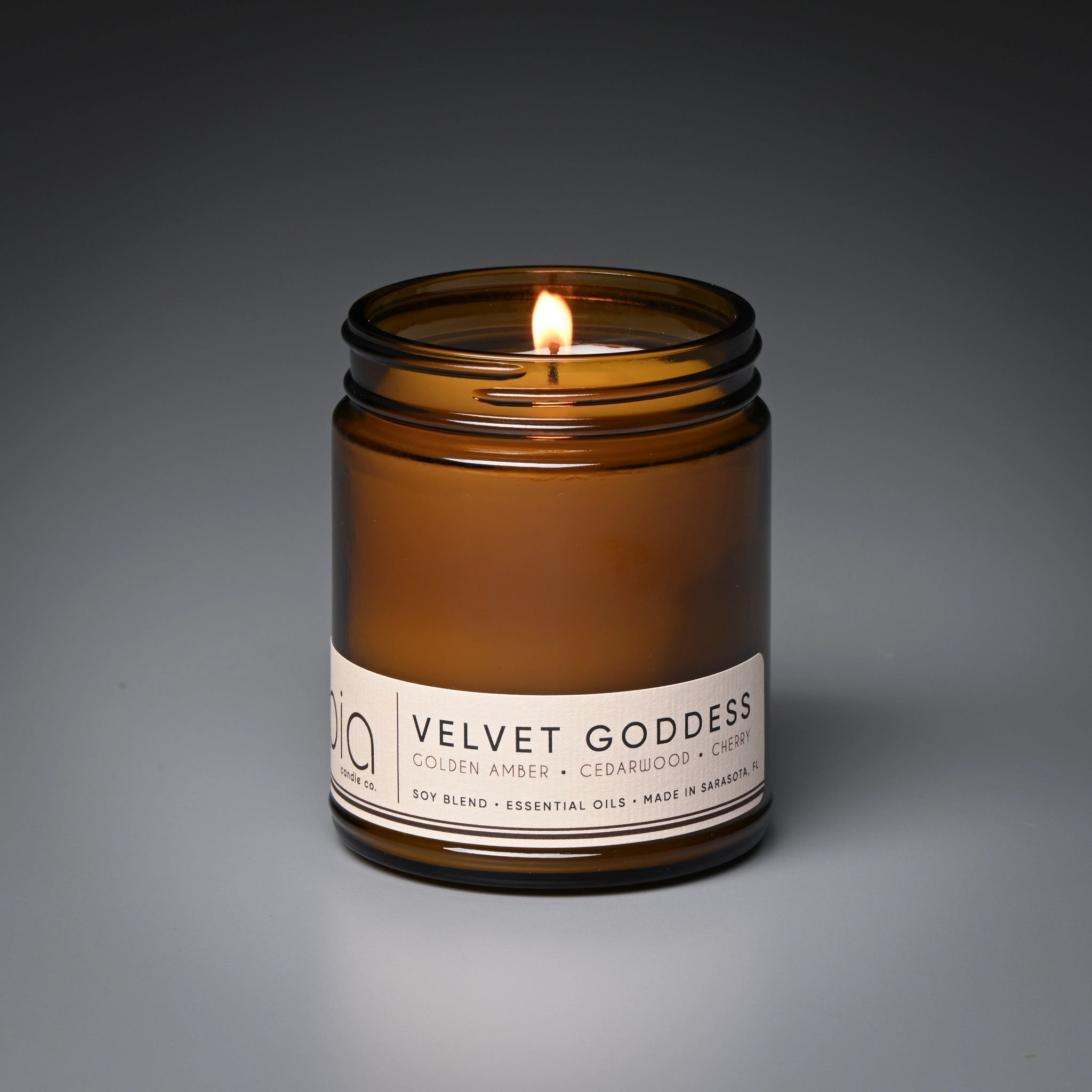 Candle in an amber jar labeled 'Velvet Goddess' on a gray background