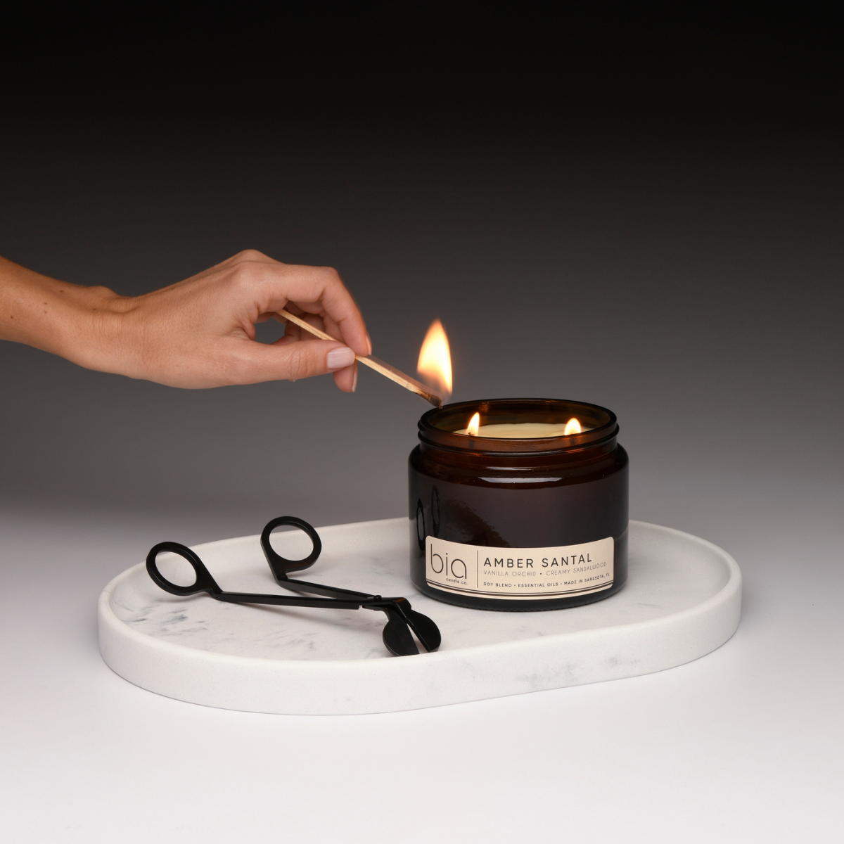 amber santal being lit with wick trimmer