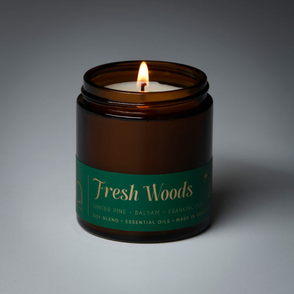 lit petite single wick holiday fresh woods soy candle on grey background