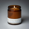 lit single wick fresh woods soy candle on grey background