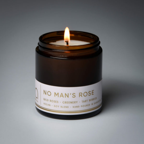 lit petite single wick no mans rose soy candle on grey background