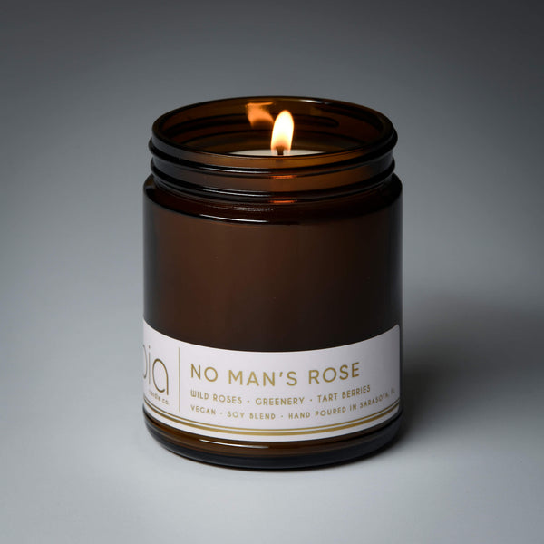 lit single wick no mans rose soy candle on grey background