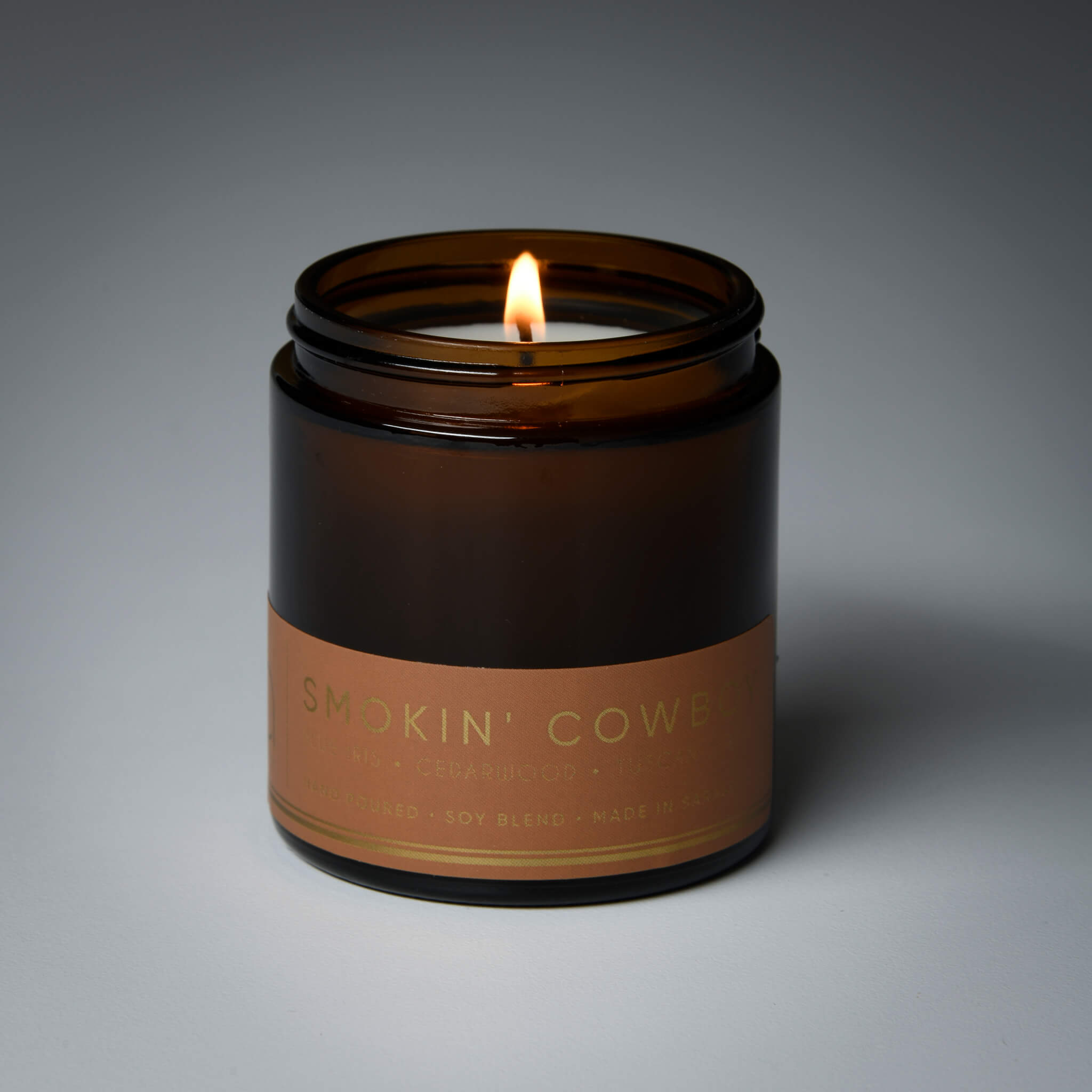 lit petite single wick smokin cowboy soy candle on grey background